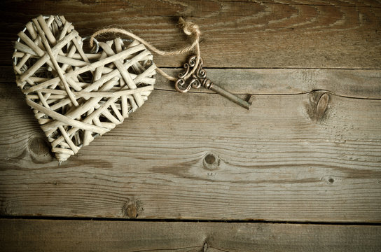 wicker heart handmade with the key lying on a wooden base