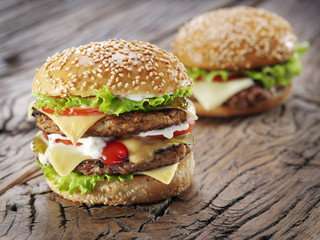 Two hamburgers on old wooden table.
