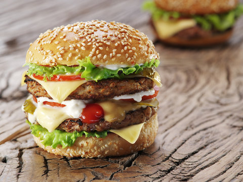 Two Hamburgers On Old Wooden Table.