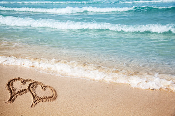 Hearts drawn on the beach sand.