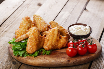 Fried chicken wings with sauce and tomatoes