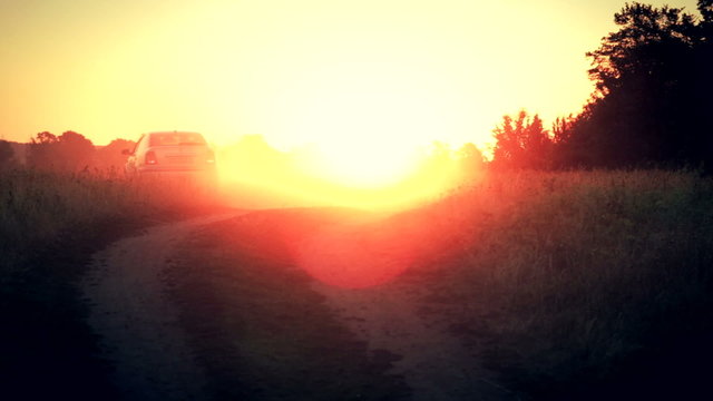The car drive away into the rays of rising sun