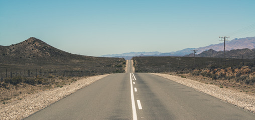 Endless road with blue sky in Swartberg semi desert landscape. W - obrazy, fototapety, plakaty