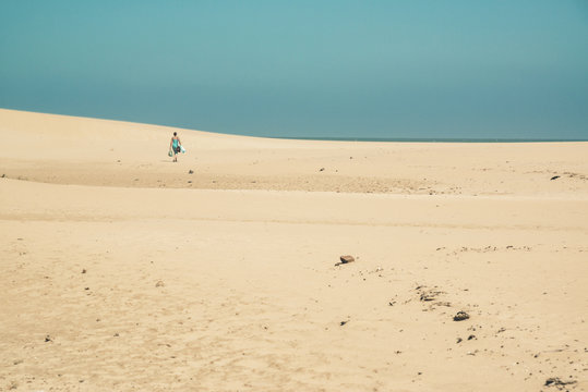 Bright sand dunes with female tourist walking to the horizon. Cl