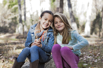 Fototapeta premium Niñas sentadas sobre piedra en el bosque