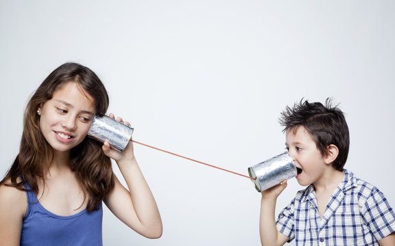 Kids using a can as telephone against gray background