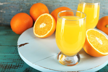 Glass of orange juice with slices on color wooden background