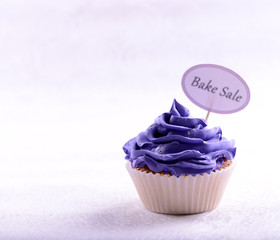 Delicious cupcake with inscription on table on beige background