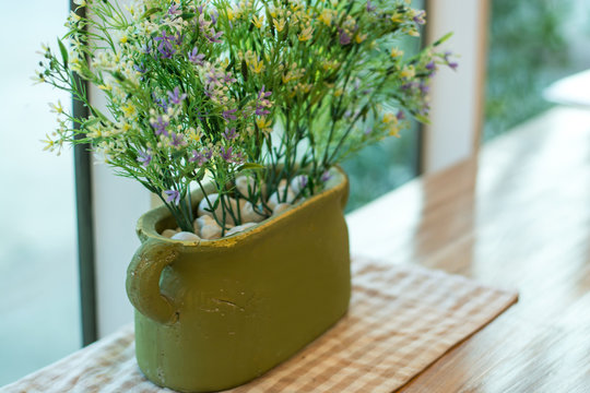 Green pot whit Plastic Flower on Wood table retro style