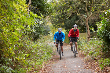 Naklejka premium Two Mature Male Cyclists Riding Bikes Along Path