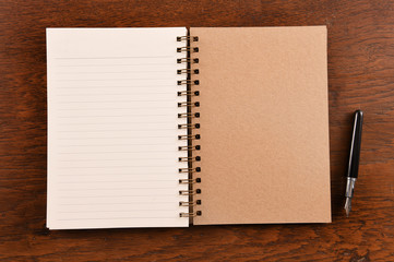 Open notebook and pen on wooden background.