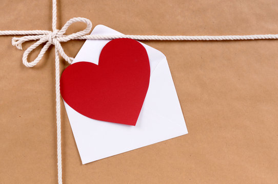 Brown paper package parcel background with red valentine heart shape card gift tag or love message and envelope photo