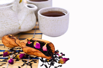 Black tea with rose petals on white background