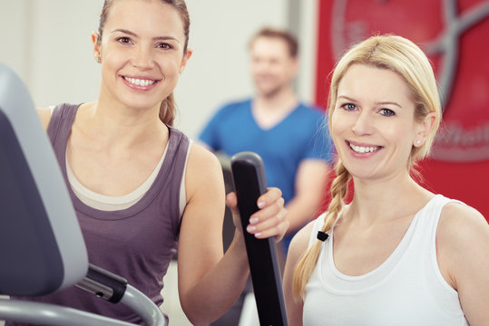 zwei lächelnde frauen trainieren im fitness-center