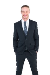 Smiling businessman in suit with hands in pocket posing