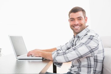 A smiling man using laptop at a table