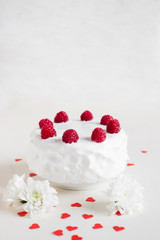 Obraz na płótnie Canvas White cake with raspberries and red hearts on white background