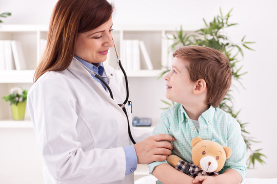 Beautiful female doctor examining smiling child
