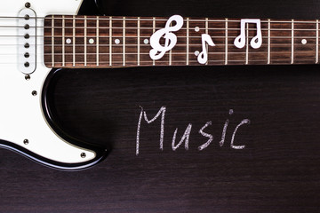 Electric guitar deck with word "music" on dark background