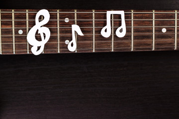 Electric guitar deck with paper treble clef on dark background