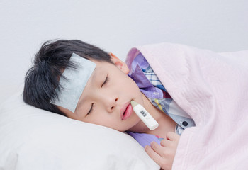 Little sick boy sleeping with digital thermometer in mouth