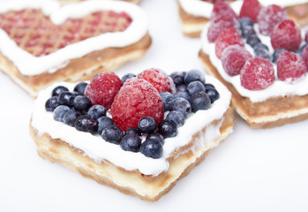 Waffle cookies in the form of hearts decorated with whipped crea