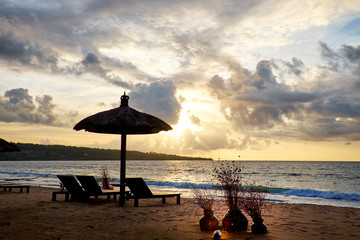 Beautiful beach with deck chairs and parasol at sunset