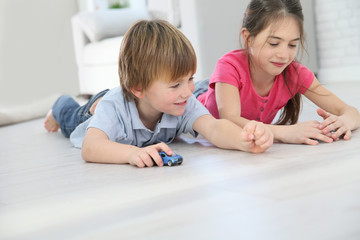 Kids playing with toy cars laying on floor © goodluz