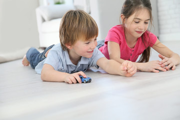 Kids playing with toy cars laying on floor
