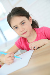 Portrait of brunette school girl writing on paper