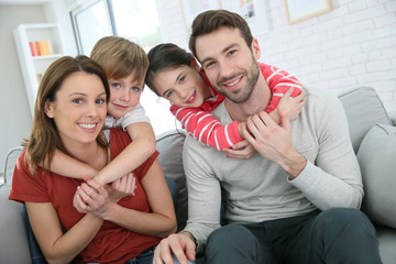 Cheerful family at home sitting in sofa