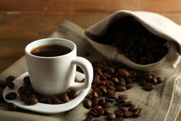 Cup of coffee with beans on rustic wooden background