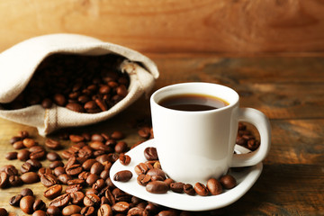 Cup of coffee with beans on rustic wooden background