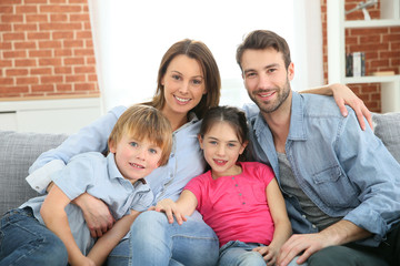 Obraz premium Cheerful family at home sitting in sofa