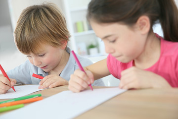 School kids sitting at table and writing on paper © goodluz
