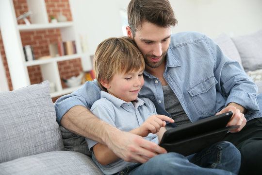 Father with little boy using digital tablet at home