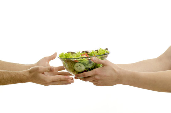 Hand offering a bowl of organic salad and other hands receiving