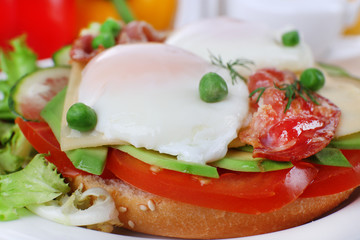 Sandwich with poached eggs, bacon and vegetables