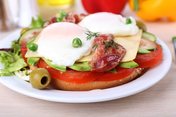 Sandwich with poached eggs, bacon and vegetables