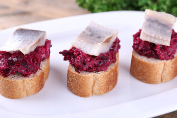 Rye toasts with herring and beets on plate close up