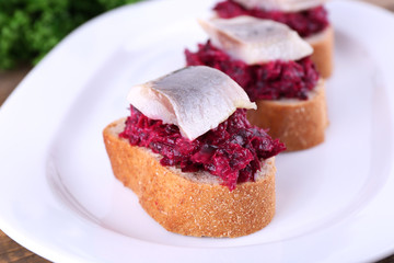 Rye toasts with herring and beets on plate close up