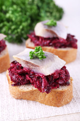 Rye toasts with herring and beets on tablecloth background