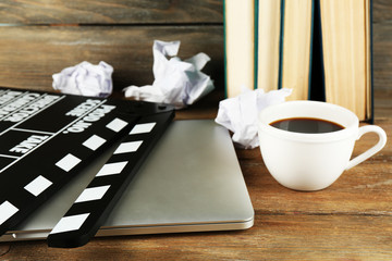 Movie clapper with laptop and cup of coffee on wooden