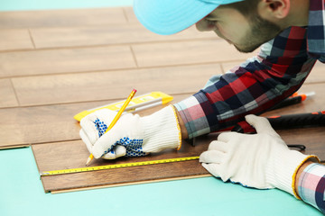 Carpenter worker installing laminate flooring in the room