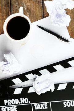 Movie clapper with paper, pen and cup of coffee