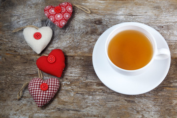 Fabric hearts and cup of tea on wooden background