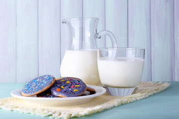 Glazed cookies with glass and jug of milk