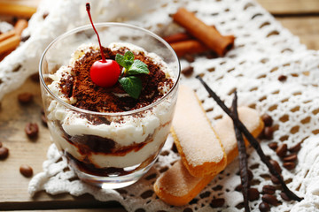 Tasty tiramisu dessert in glass, on napkin, on wooden