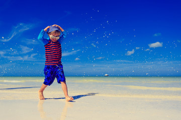 little boy splashing water on summer beach