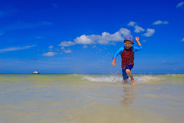 little boy playing with water on summer beach